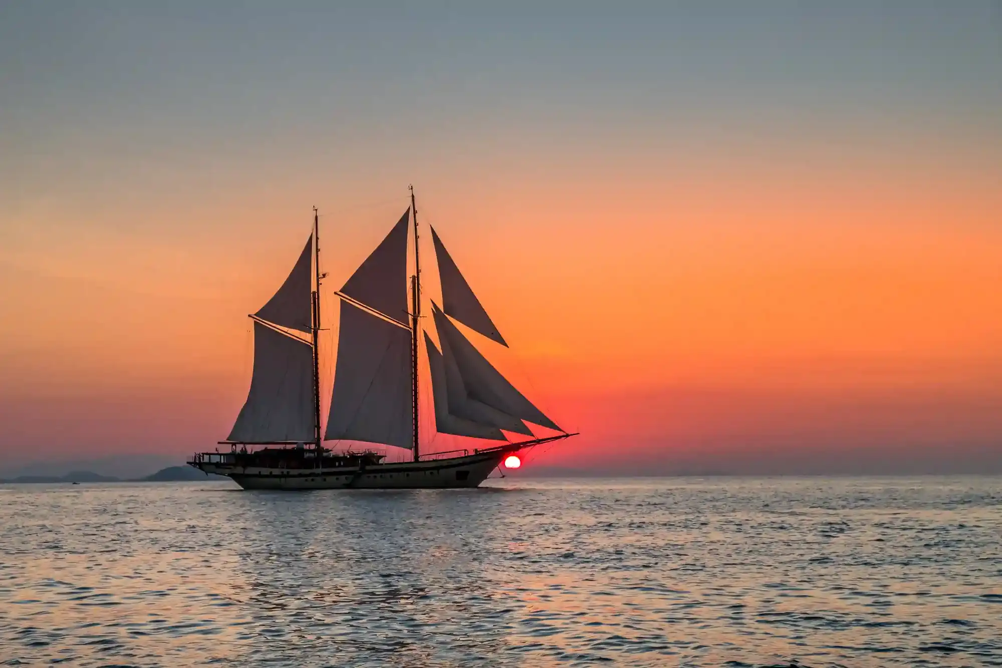 A crewed charter yacht under sail on a private Lombok diving package